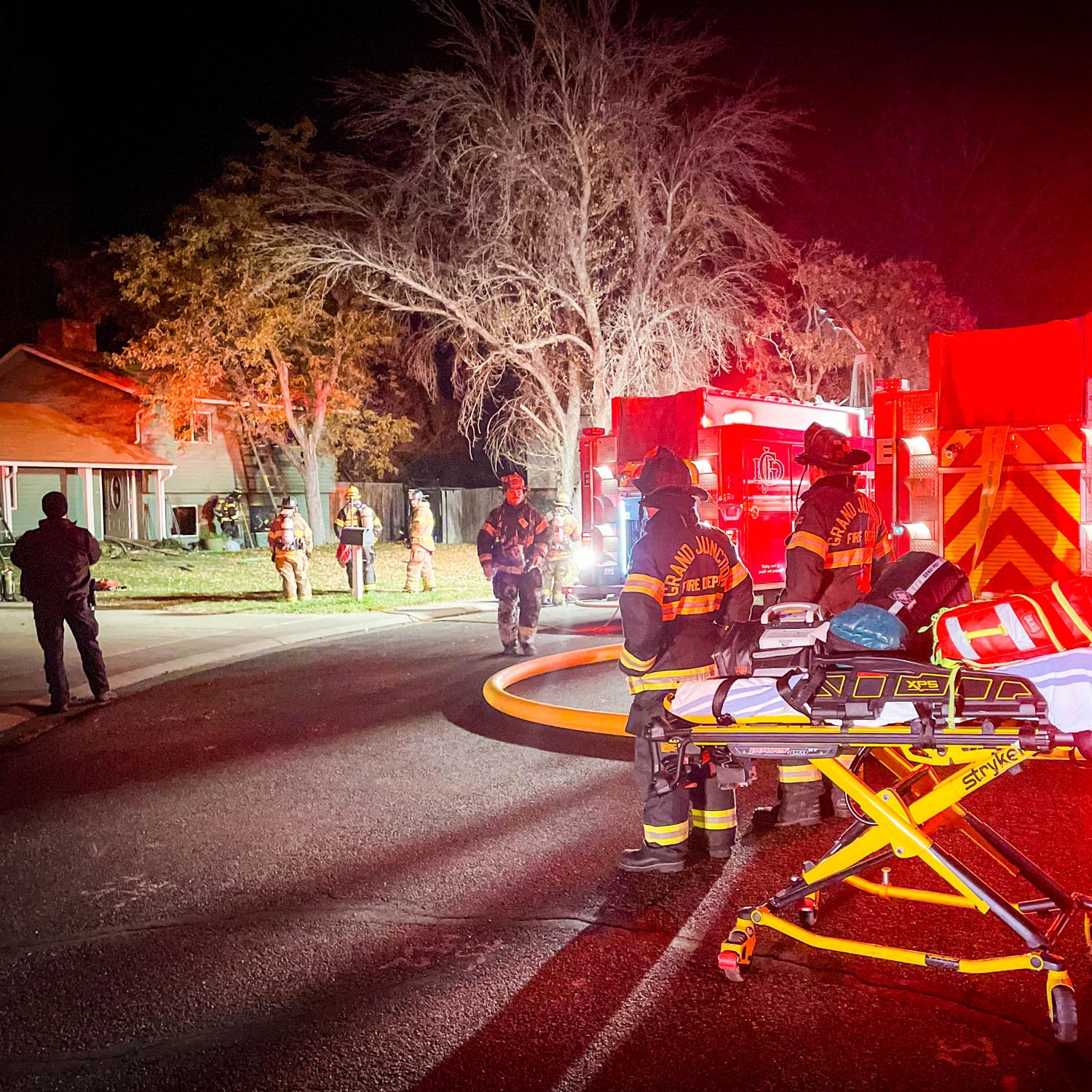 Firefighters in front of a home that has fire damage
