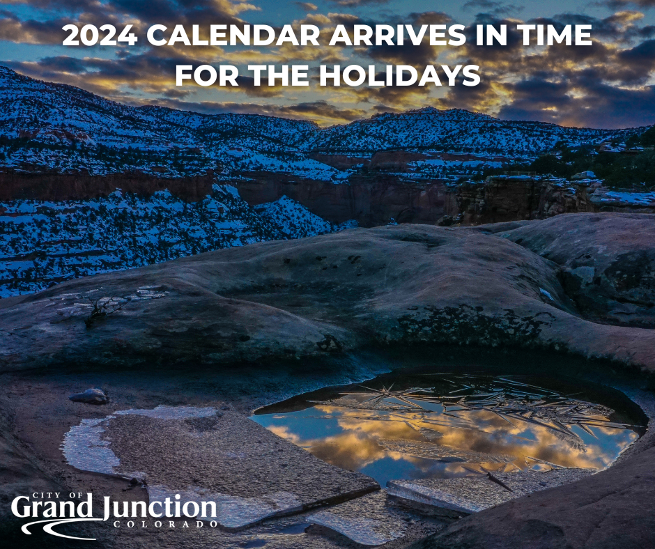 The Colorado National Monument at dusk in the background with the focus on a puddle that's frozen