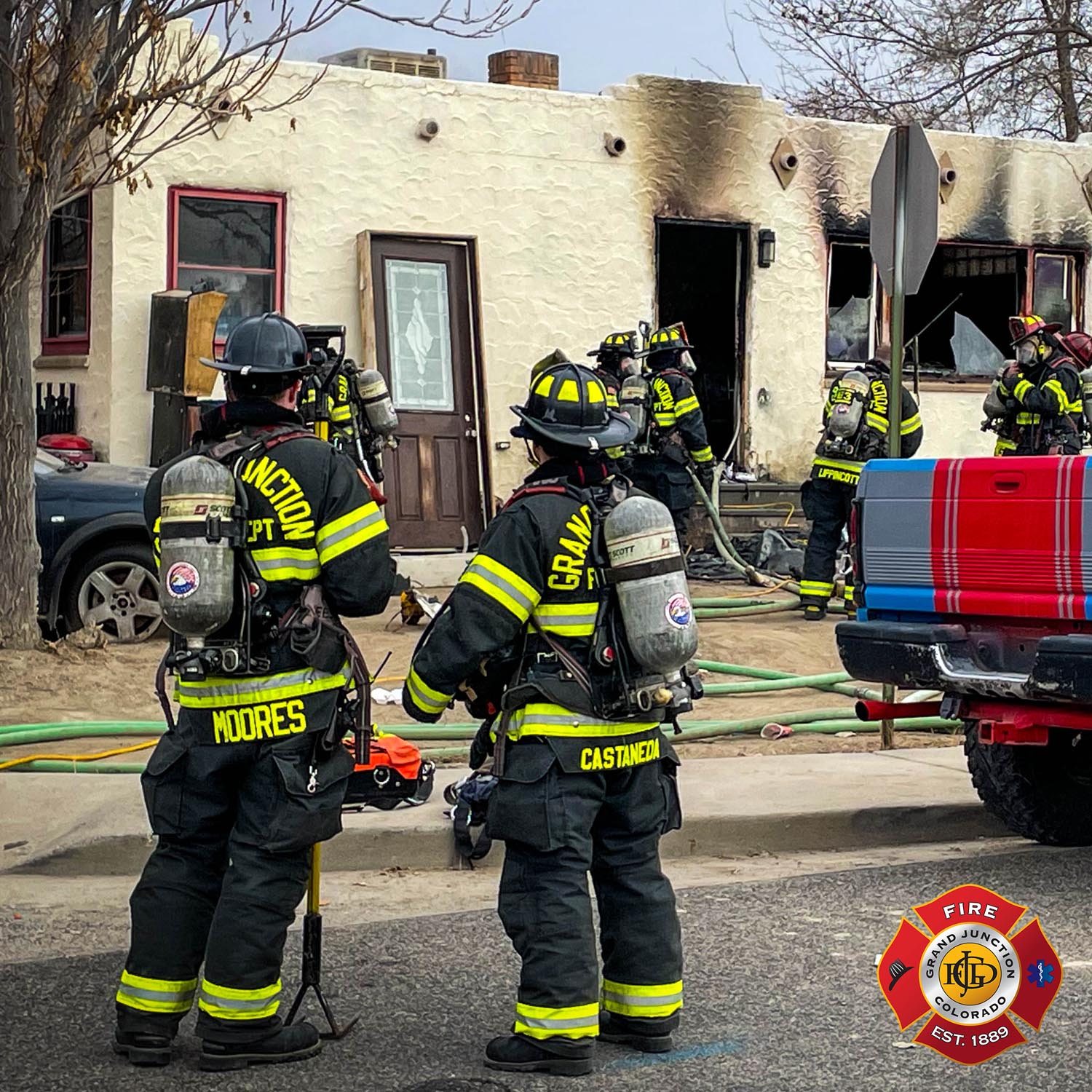 Firefighters standing in front of a burnt stucco home
