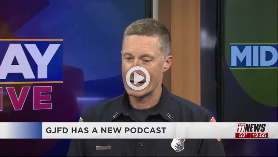 Fire employee in uniform with newsroom blue walls behind him 