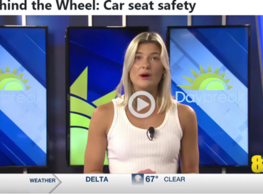News anchor at desk with blonde hair and white top with blue newsroom behind