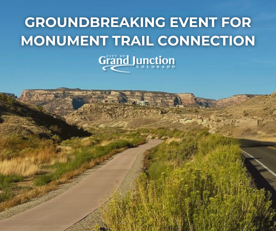 A trail winds down next to a road near the Colorado National Monument midday.