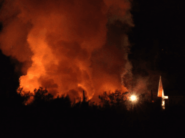 Fire and smoke at night, silhouetted trees