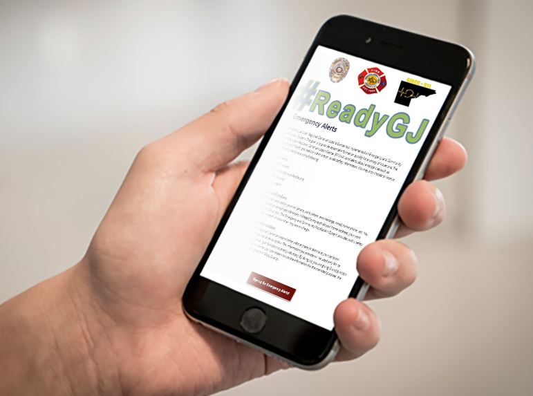 hand holding phone to register for emergency alerts