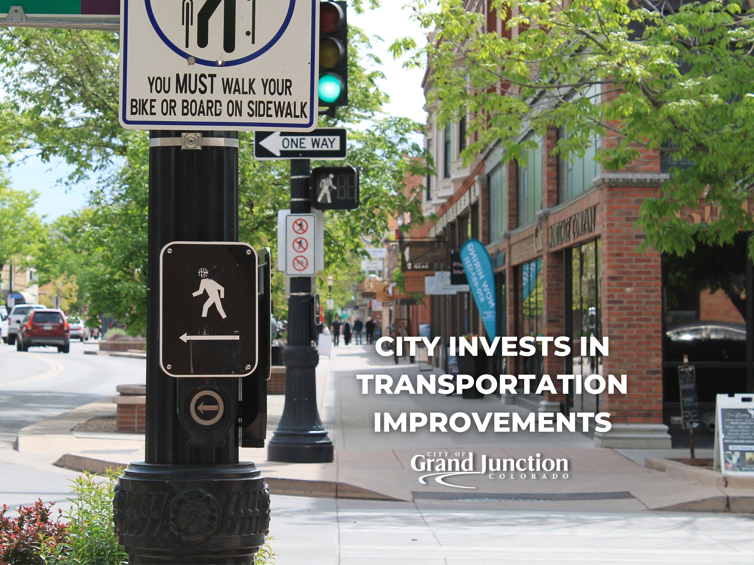 View of downtown Grand Junction with cross walk sign present. Text on image. Outside.