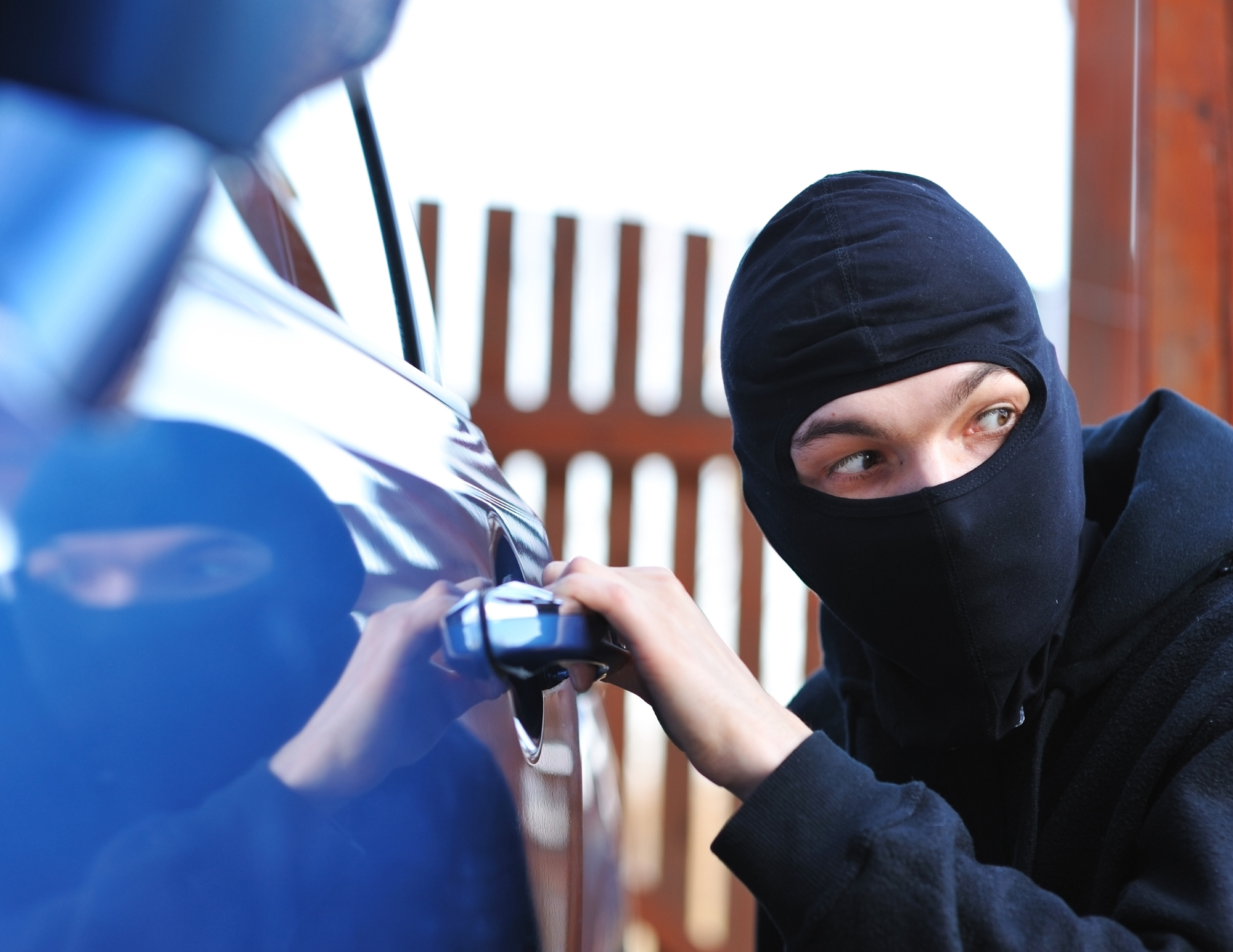 image of man in mask breaking into a car