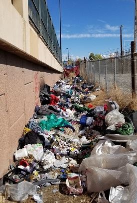 Debris and waste buildup between wall and fence.